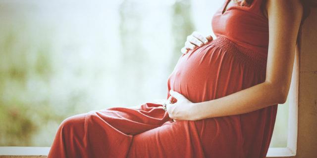 Ecco i consigli per viaggiare durante le prime settimane di gravidanza Una donna incinta vestita di rosso