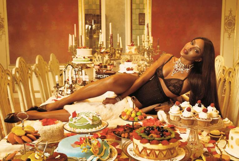 Naomi Campbell e un tavolo di dolci Naomi Campbell adagiata su un tavolo di cibo e dolci