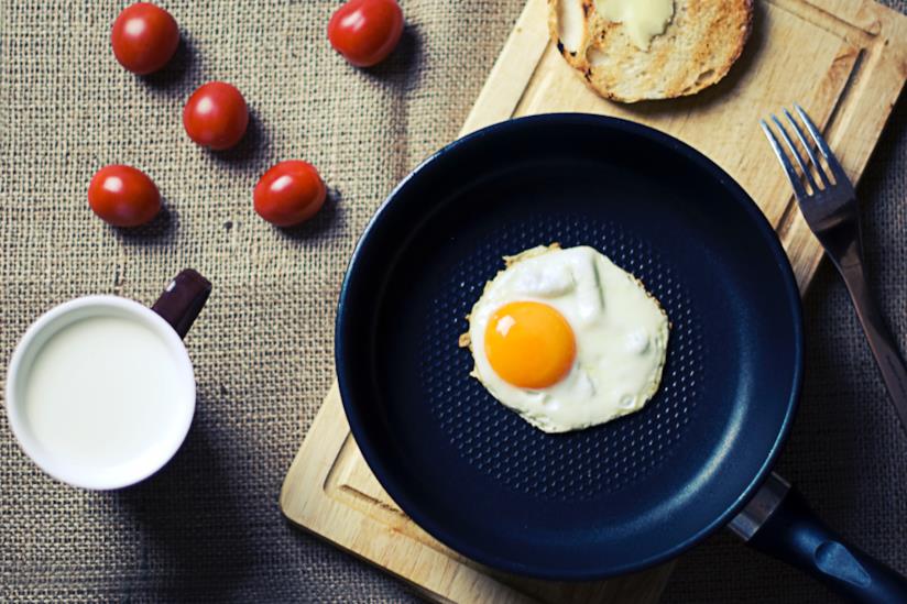 Una padella antiaderente con un uovo Ingredienti per una colazione di uova e pomodori
