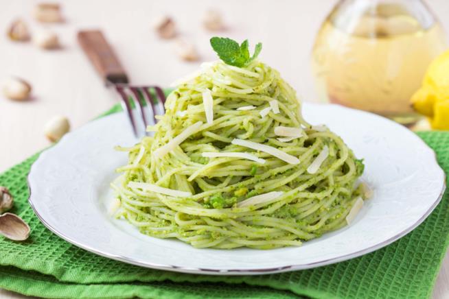 Spaghetti con pesto di pistacchi: la ricetta Primo piano di spaghetti con pesto di pistacchi e scaglie di parmigiano, serviti a forma di nido