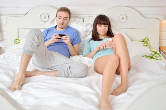 Una coppia impegnata al cellulare Due fidanzati si ignorano mentre chattano con altri