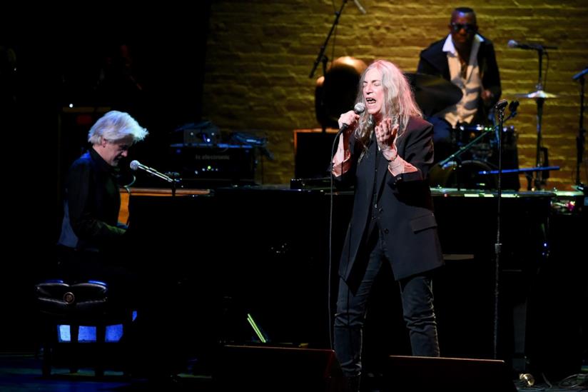 Patti Smith canta Patti Smith, vestita di nero, canta al microfono, accompagnata da un pianista