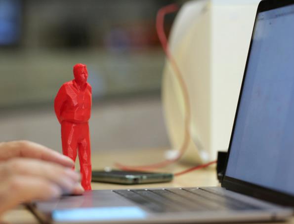 Fuorisalottino, tra statue in miniatura, fotografie e oggetti piccoli Statuetta rossa di un uomo in miniatura, vicino a un computer