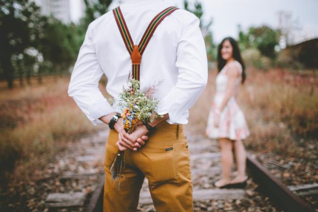 Cose che fanno innamorare le donne: ecco 10 piccole attenzioni che danno gli uomini per farci perdere la testa. Un uomo di spalle con un mazzo di fiori in mano.