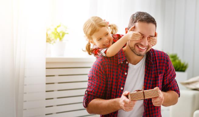 La festa del papà in Italia e nel mondo Una bambina spunta alle spalle del padre che ha un suo regalo