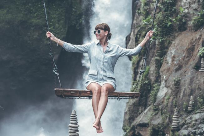 Frasi sulla bellezza Ragazza su un'altalena in un paesaggio da sogno
