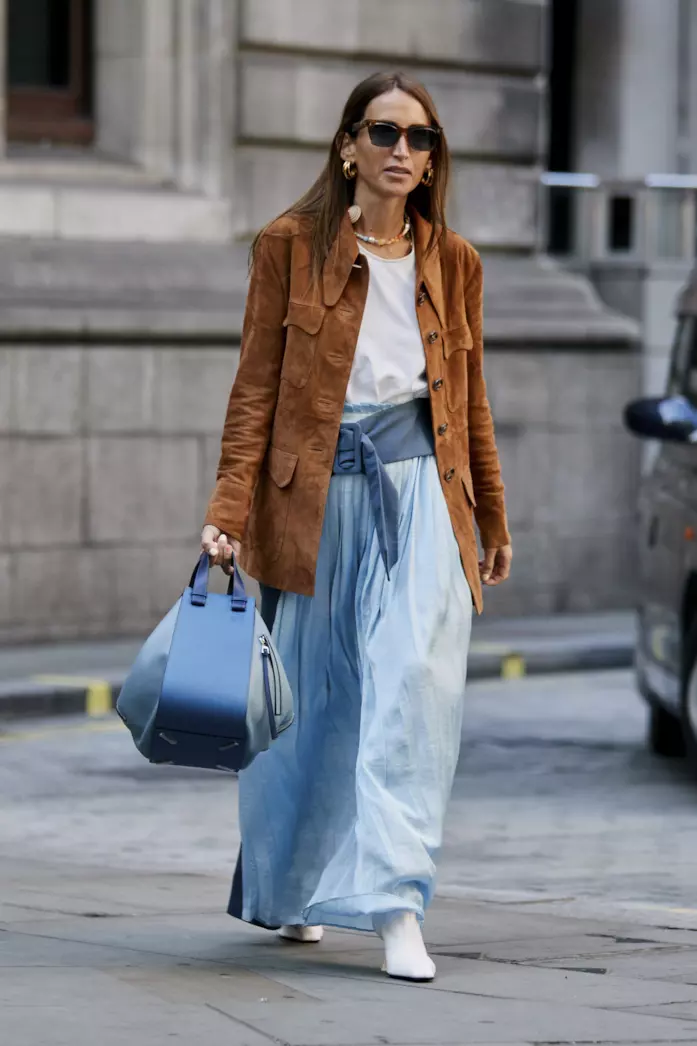Una gonna azzurra in raso abbinata a giacca scamosciata e ankle boots Una maxi skirt in raso indossata con giacca e ankle boots bianchi