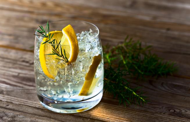 I numerosi benefici nel consumare regolarmente gin Un bicchiere di gin con lime e foglie di ginepro