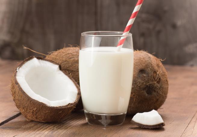 Il latte di cocco è benefico per la salute Un bicchiere di latte di cocco con il frutto stesso
