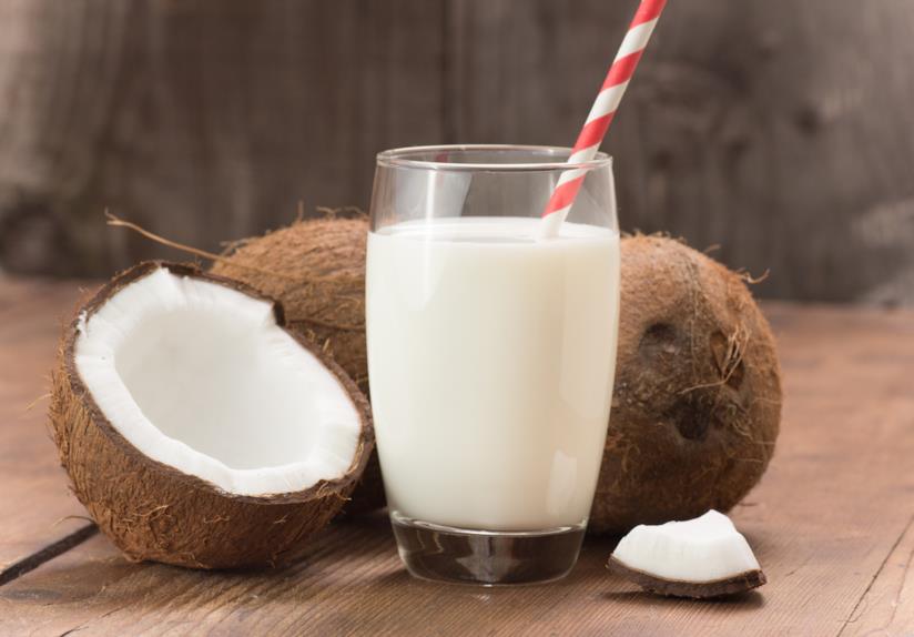 Il latte di cocco è benefico per la salute Un bicchiere di latte di cocco con il frutto stesso