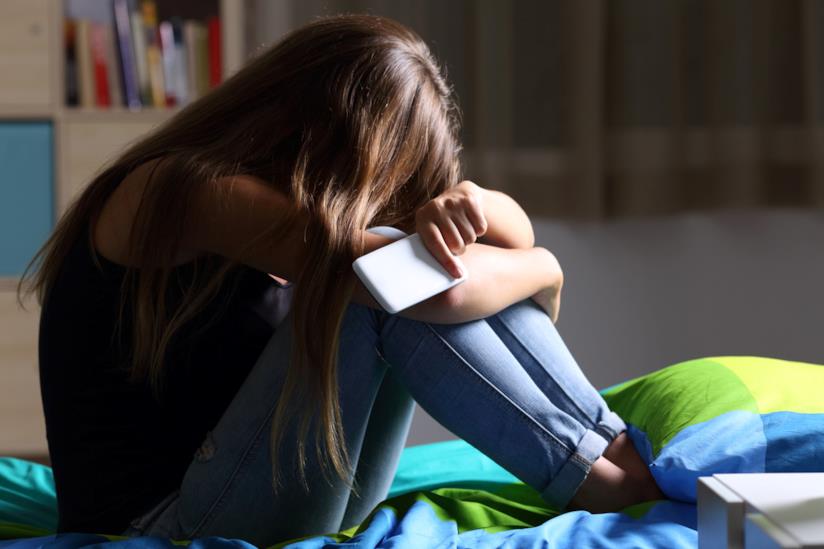 Recenti indagini hanno notato come l'astinenza da social network presenta gli stessi sintomi di quella da droghe. Una ragazza sconsolata che tiene in mano il cellulare.