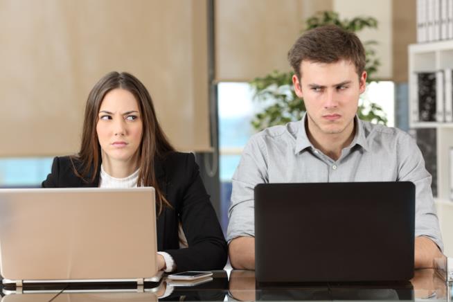 Sessismo sul post di lavoro Un uomo e una donna in ufficio si guardano male