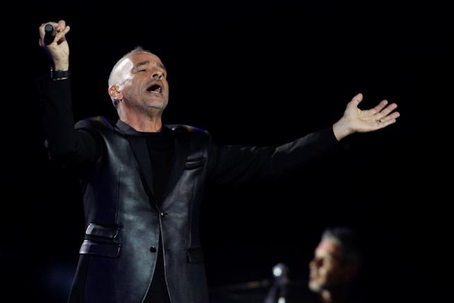 Eros Ramazzotti in concerto Eros Ramazzotti, innero, su sfondo nero, in piedi, con il microfono in piano e le braccia aperte