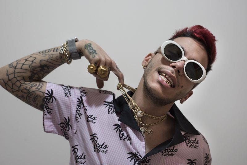 Sfera Ebbasta al Concerto del Primo Maggio Primo piano di Sfera Ebbasta, con gli occhiali da sole e che tiene con un dito le sue tante collane d'oro
