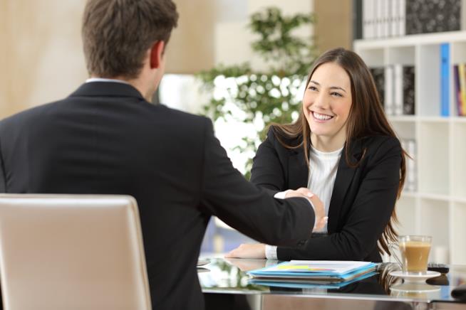 Le cose da chiedere e da sapere quando si sta per essere assunti Un uomo e una donna in ufficio si stringono la mano