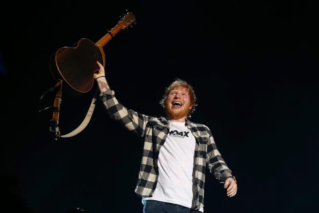 Ed Sheeran in Italia nell'estate 2019 Ed Sheeran, sorridente, in piedi, tiene la chitarra sollevata con la mano sinistra