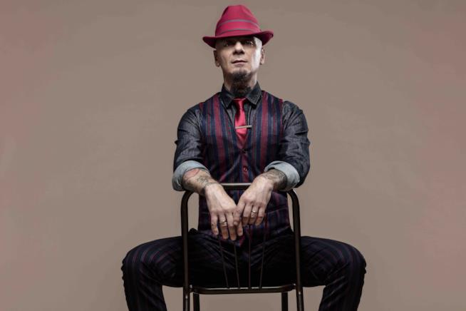 J-Ax torna con un nuovo singolo J-Ax seduto al contrario su una sedia, con la cravatta e il cappello rossi