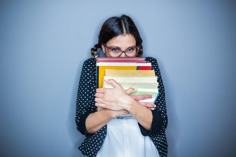 Una donna insegnante con libri in mano Una ragazza si nasconde dietro a dei libri