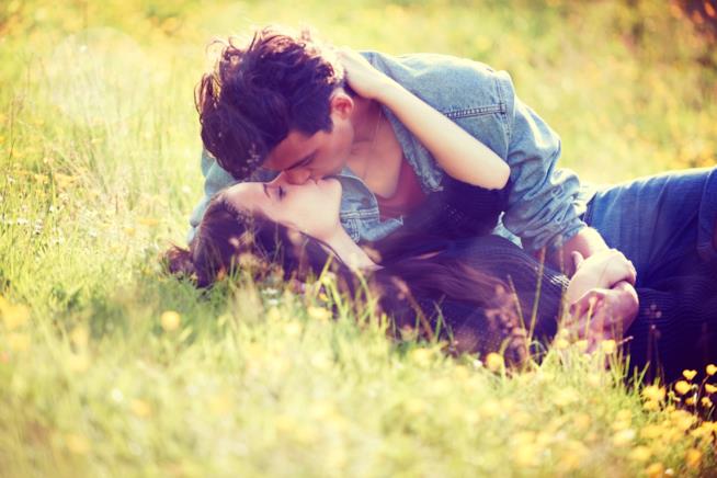 Le frasi più belle da dedicare a lui per San Valentino Una giovane coppia si bacia su un prato