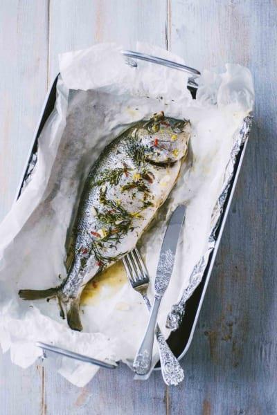 Orata al cartoccio con olio, sale, pepe e rosmarino Orata al cartoccio cotta in forno