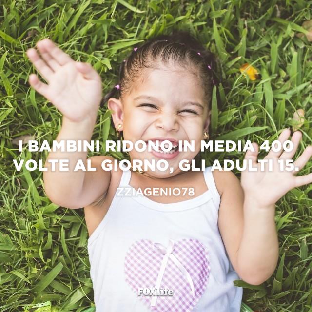 Frase sul sorriso dei piccoli Bambina sdraiata in un prato sorride a mani alzate