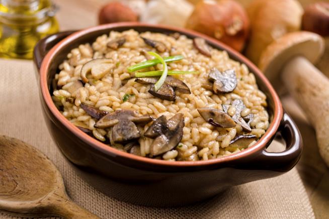 Risotto con funghi porcini: la ricetta Tegame in primo piano con riso, funghi porcini e qualche filo di erba cipollina.