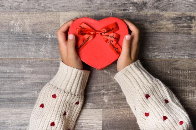 Un regalo di San Valentino Le braccia di una ragazza che tiene in mano un regalo si San Valentino