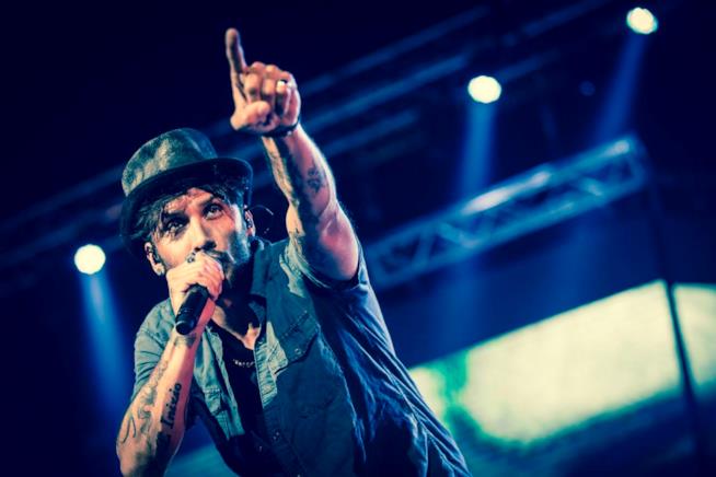 Fabrizio Moro: altre tre date quest'estate Fabrizio Moro con il cappello e il braccio sinistro alzato, nella mano destra il microfono