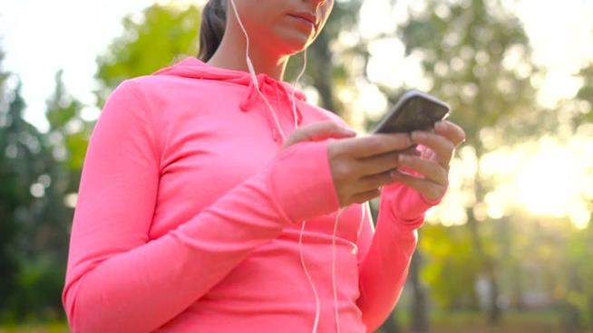 Una ragazza fa sport con uno smartphone Smartphone e sport possono andare d'accordo