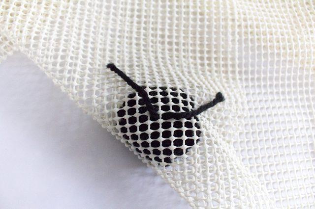 Inserite il pom pom nel tappeto a rete Dettaglio del pom pom inserito nel tappeto