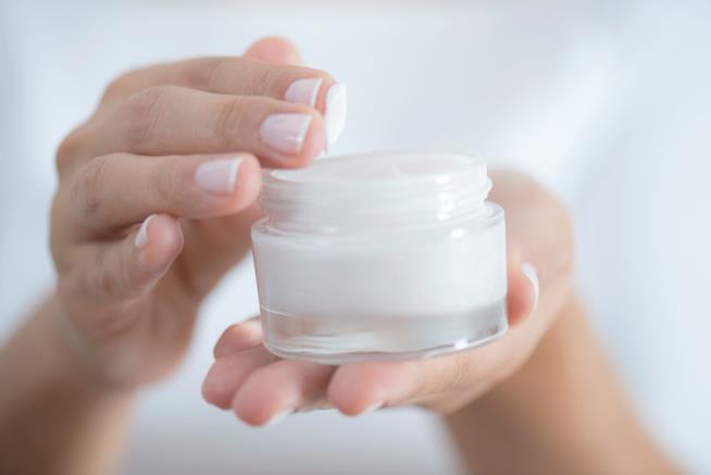 Guarire dall'eczema usando dei prodotti naturali per la cosmesi Dettagli di una mano di donna che prende della crema da un vasetto