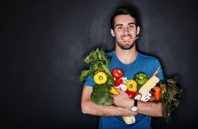 La dieta vegana non è davvero senza violenza Un ragazzo stringe al petto dei vegetali tenendo una carota in bocca