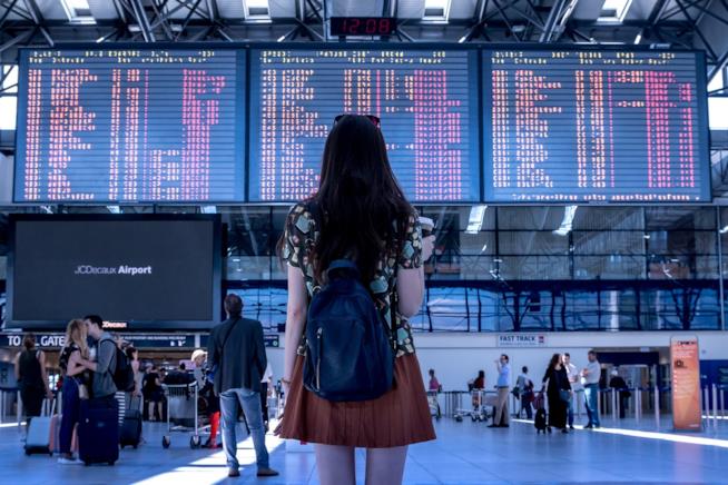 Viaggi e consigli: i segreti (svelati) da chi è sempre con la valigia in mano. Una donna di spalle in aeroporto.