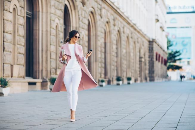 Le dritte per far sembrare più costoso il tuo look Ragazza in bianco con cappotto rosa passeggia