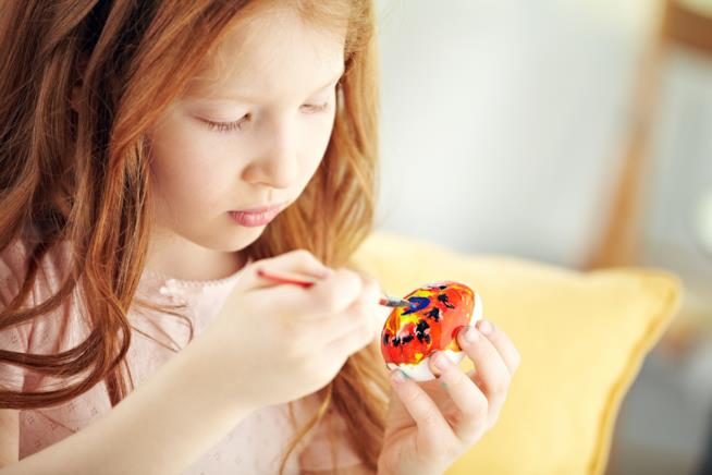 Decorazioni Pasquali dai da te Bambina dipinge un uovo