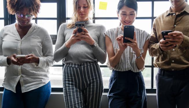 Tre donne con un cellulare in mano Tre donne in piedi consulano i cellulari