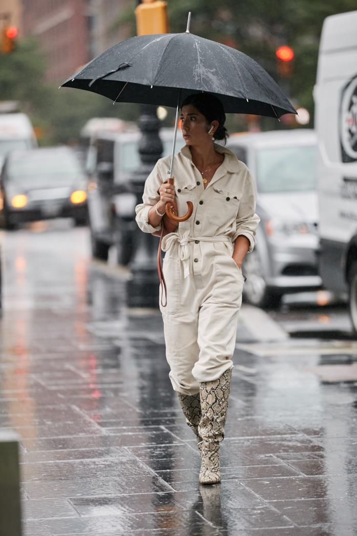 Jumpsuit bianca indossata con stivali alti pitonati Jumpsuit bianca abbinata a stivali alti pitonati