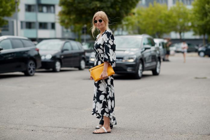 Infradito abbinate a maxi dress a fiori e maxi pochette Sandali flat indossati con abito a fiori e pochette in formato maxi