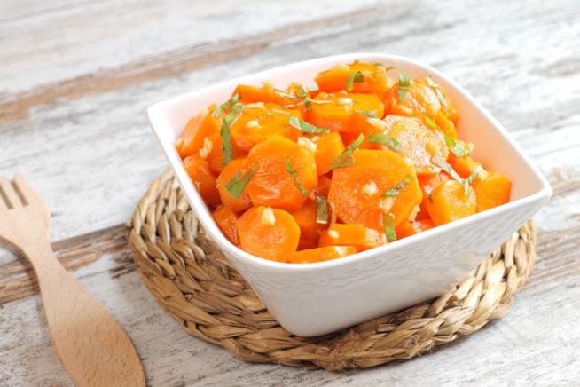 Carote marinate: la ricetta Tegame quadrato di porcellana su sottopentola di paglia intrecciato con carote, aglio e prezzemolo