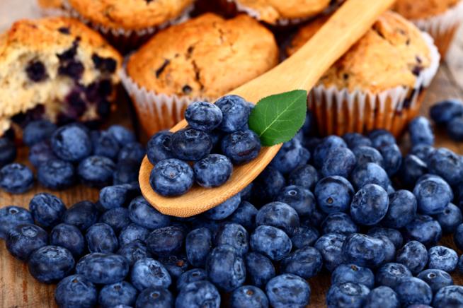 Ricetta veloce di muffin ai mirtilli Muffin ai mirtilli su un tagliere di legno ricoperto da mirtilli freschi
