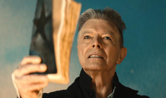David Bowie nel video di Blackstar Un'immagine dal video di Blackstar di David Bowie, mentre alza il libro con la stella nera