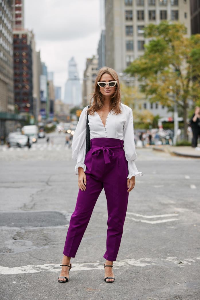 Camicia bianca indossata con pantaloni viola a vita alta e sandali neri Camicia bianca abbinata a pantaloni viola a vita alta e sandali neri