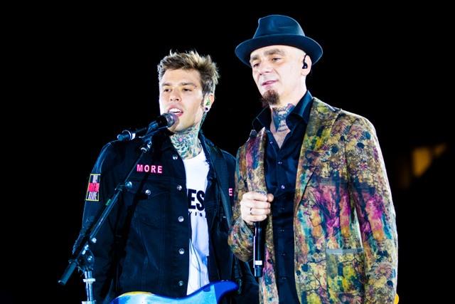 Fedez e J-Ax a San Siro Fedez in nero, con una t-shirt bianca. J-Ax con cappello e giacca colorata. Cantano al microfono