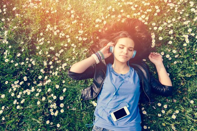 ASMR per dormire bene e ritrovare il benessere psico-fisico Una ragazza sdraiata in un prato si rilassa ascoltando musica