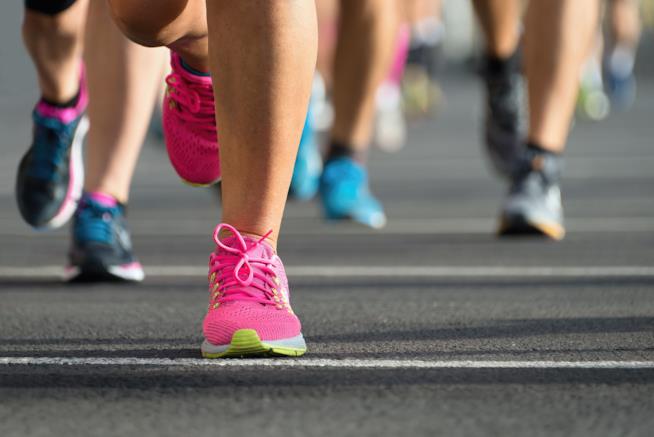 Le migliori mete nel mondo per gli appassionati di maratona scarpe sportive rosa in primo piano e altre persone dietro sullo sfondo che corrono