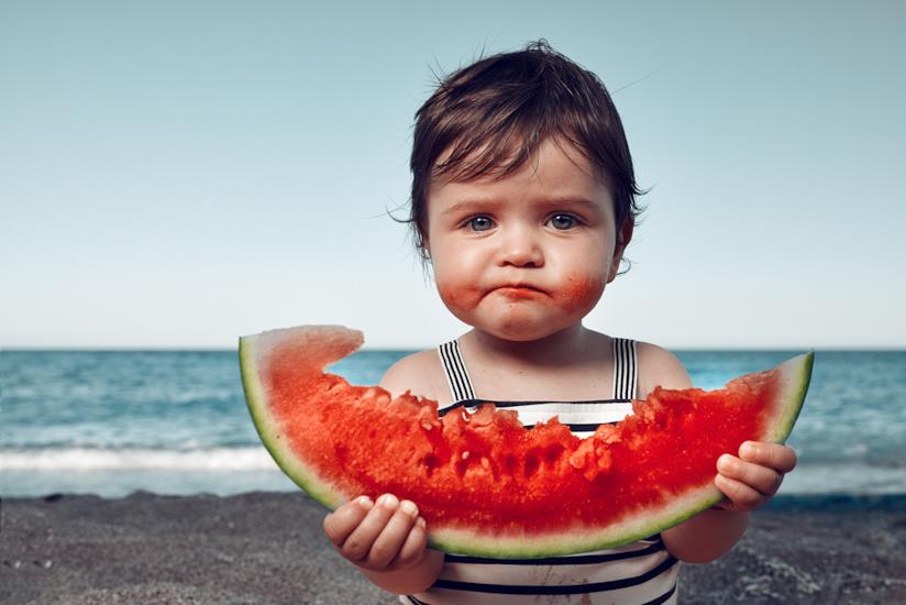 Cibi da evitare quando fa caldo Bambino con una fetta di cocomero in mano