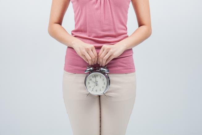 Tutto sulla Proposta di Legge sul congedo mestruale Orologio sveglia in mano di donna