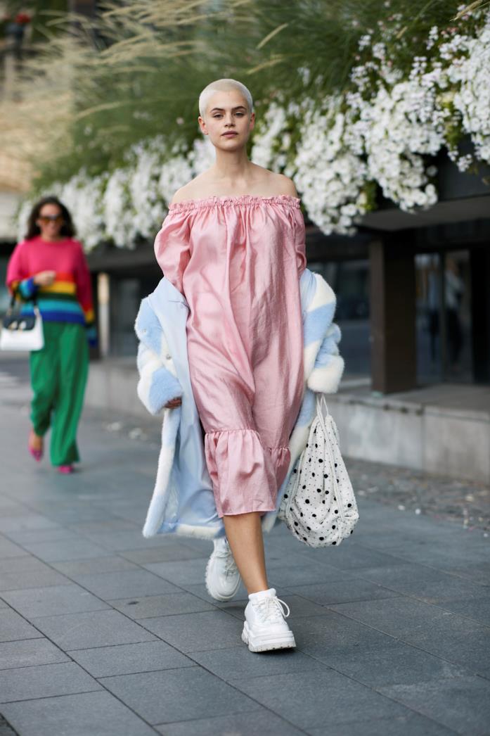Sneakers bianche abbinate a un abito rosa con le spalle scoperte Sneakers bianche indossate con abito midi e borsa a mano