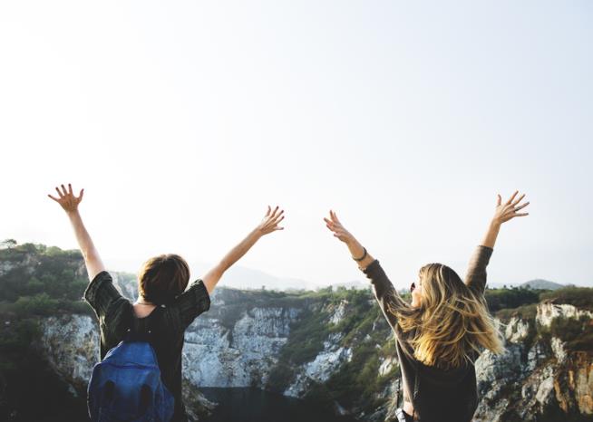 A cosa si è disposti a rinunciare pur di viaggiare gratis? Ecco cosa ha dimostrato uno studio condotto su 1500 millennials Due ragazze felici fotografate di spalle.