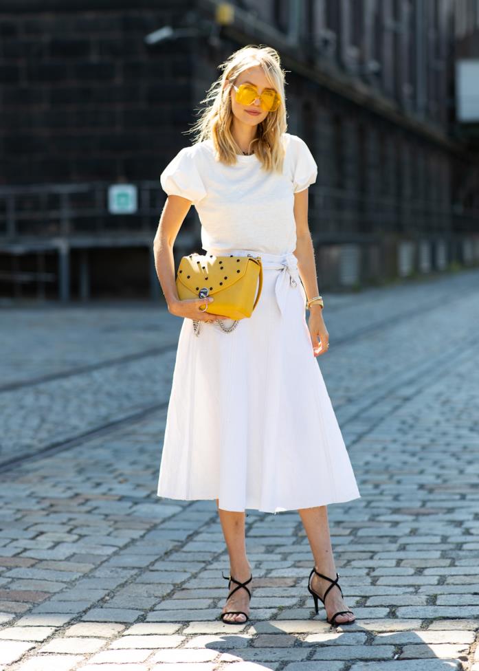 Look total white con accessori a contrasto Un look total white composto da blusa a maniche corte e gonna midi